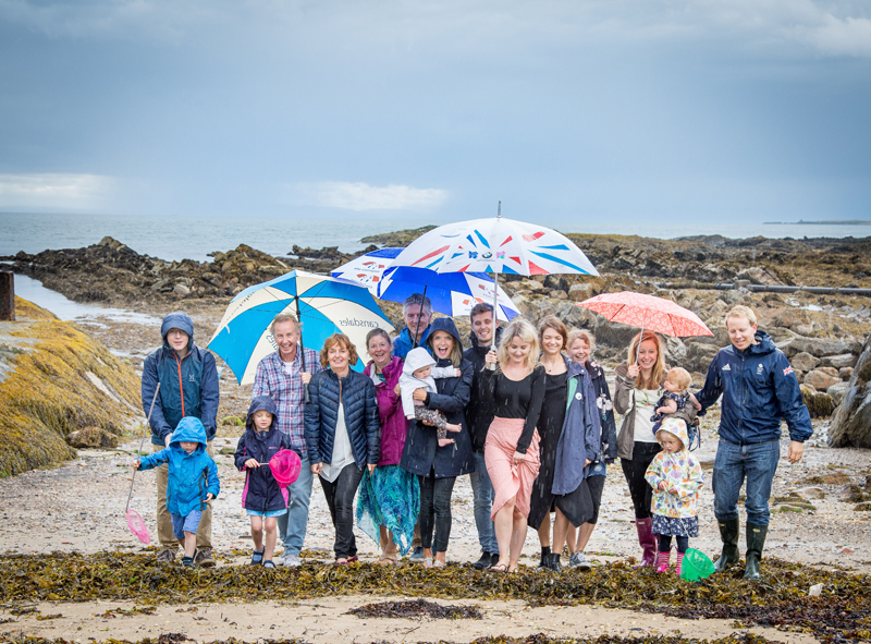 Family portrait on the beach at  Pittenweem in the rain with umbrellas
